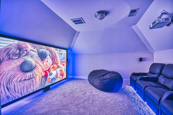 A modern living room with a large flat-screen TV, a bean bag, and a reclining sofa.