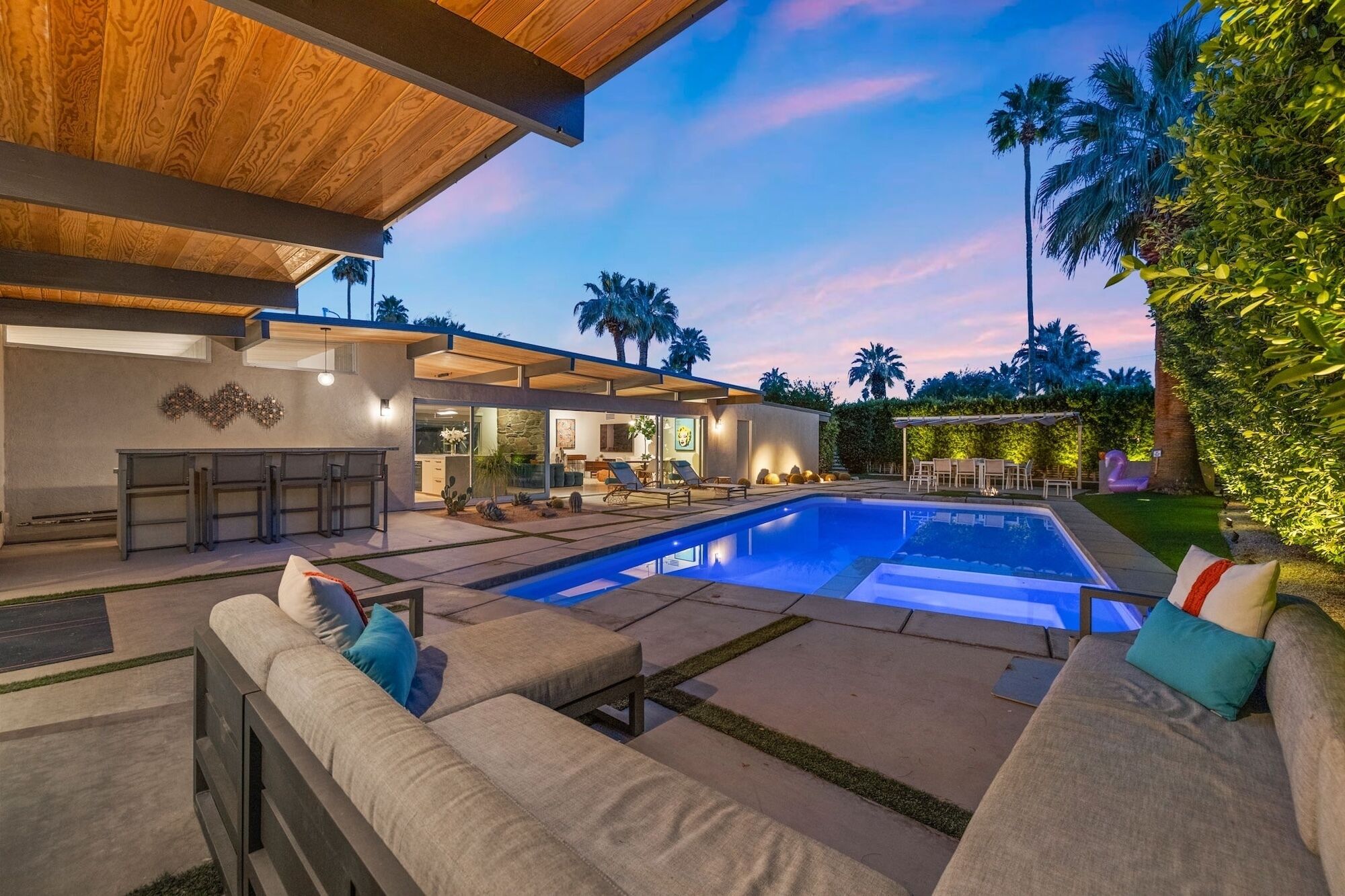 Ein modernes Haus mit Swimmingpool, Außenbereich zum Sitzen und einer überdachten Terrasse.