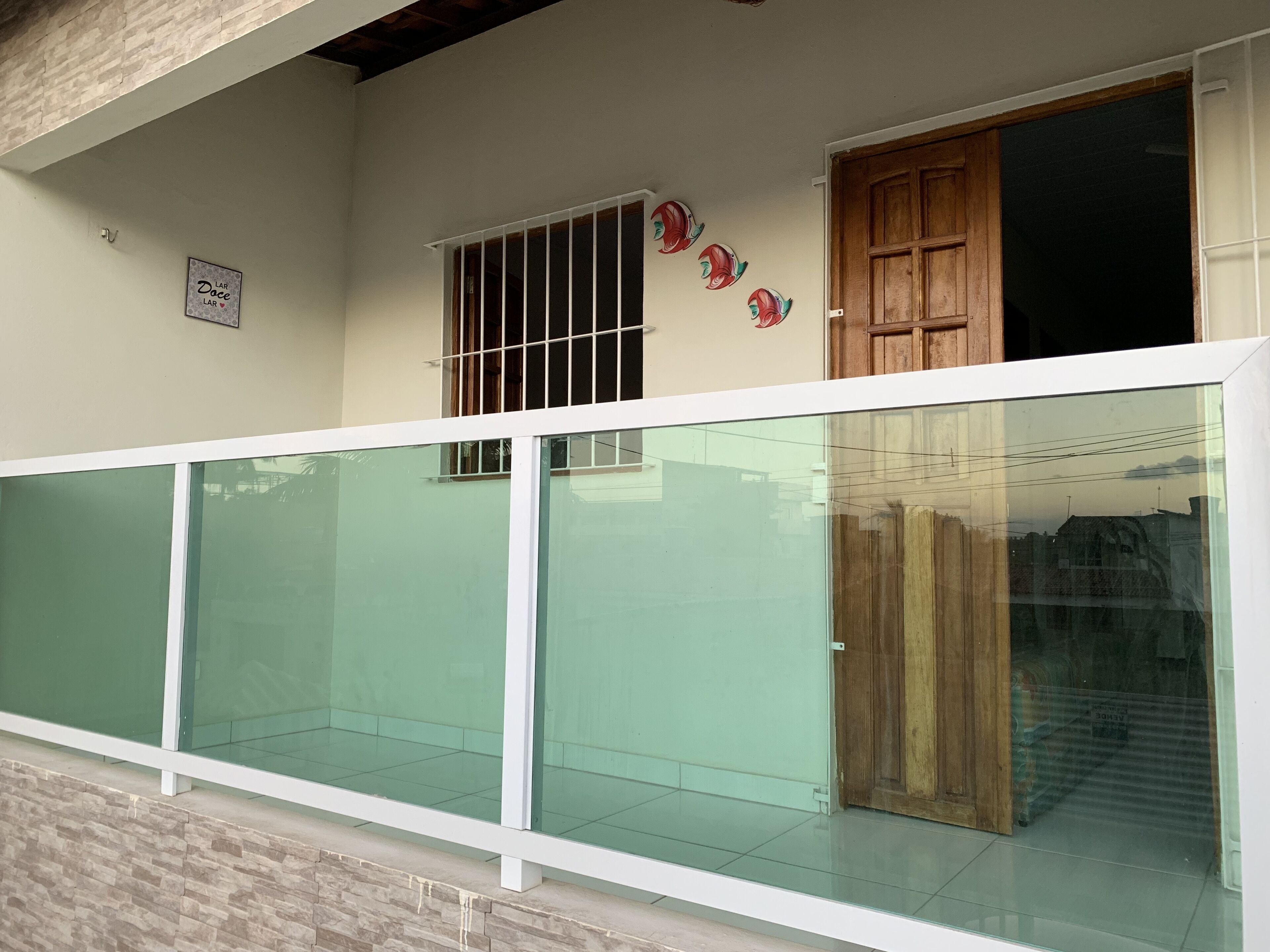 A building with a glass balcony, a wooden door, and a window with metal bars.