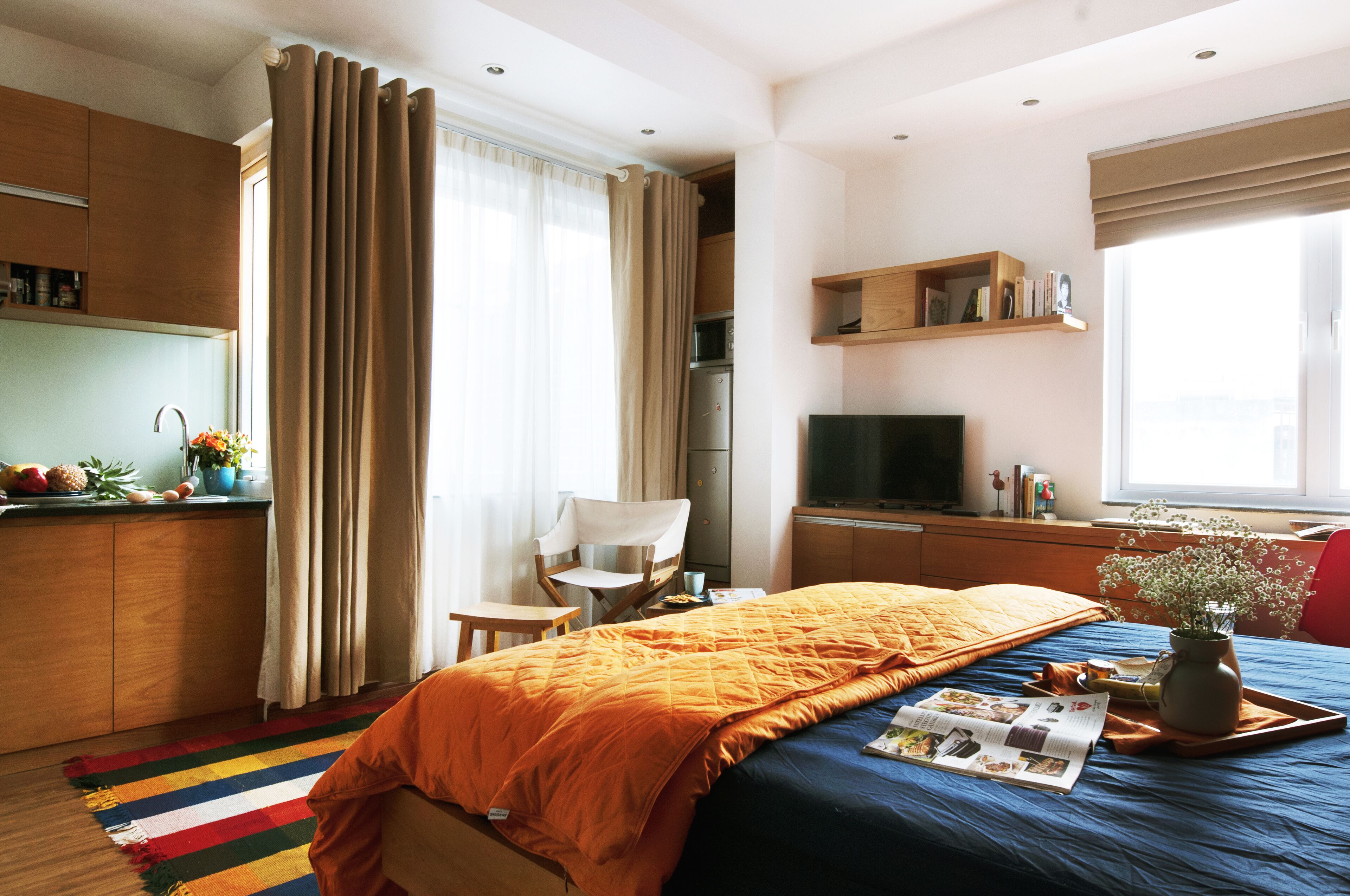 Une chambre d’hôtel comprenant un lit, une télévision, un bureau, une chaise, une fenêtre avec des rideaux et une kitchenette.