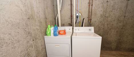 A laundry area with two washing machines, a dryer, and a laundry basket.