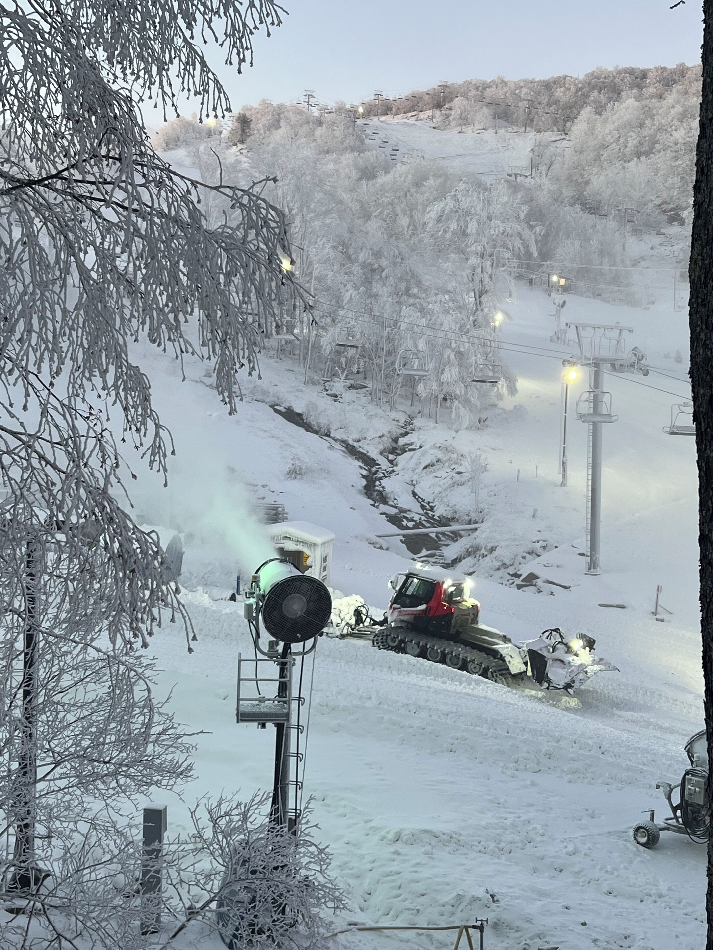Schneebedeckte Landschaft mit Seilbahn und Schneepflüger.