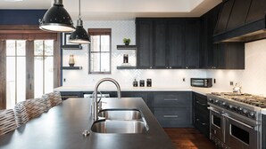 A modern kitchen with a large island, stainless steel appliances, and dark cabinetry. - Silver Star 40 | Theater Room | Hot Tub (Park City)