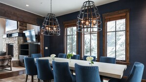 A dining area with a long table, blue chairs, and pendant lights. - Silver Star 40 | Theater Room | Hot Tub (Park City)