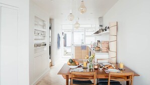 A bright kitchen with a dining table set for breakfast, featuring a fruit bowl and a vase with flowers. - 6 Barnaloft (St Ives)