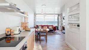 A modern kitchen with a dining area, a red sofa, and a view of the sea. - 6 Barnaloft (St Ives)