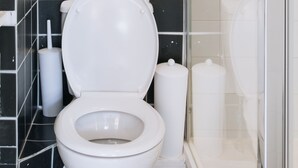 A bathroom with a white toilet, a glass shower enclosure, and black and white tiled walls. - Bright Studio Flat in Central London Zone 1 Paddington / Lancaster gate cozy (London)