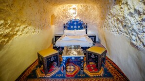 Ein kleiner, gemütlicher Raum mit einem Bett, zwei Hocker und einem Tisch.