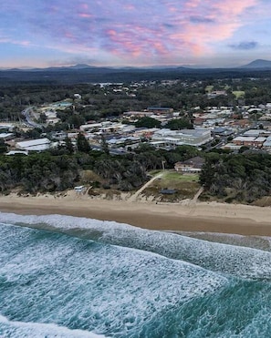 Eine Küstenstadt mit Strand, Wohnhäusern und einem Berg im Hintergrund.