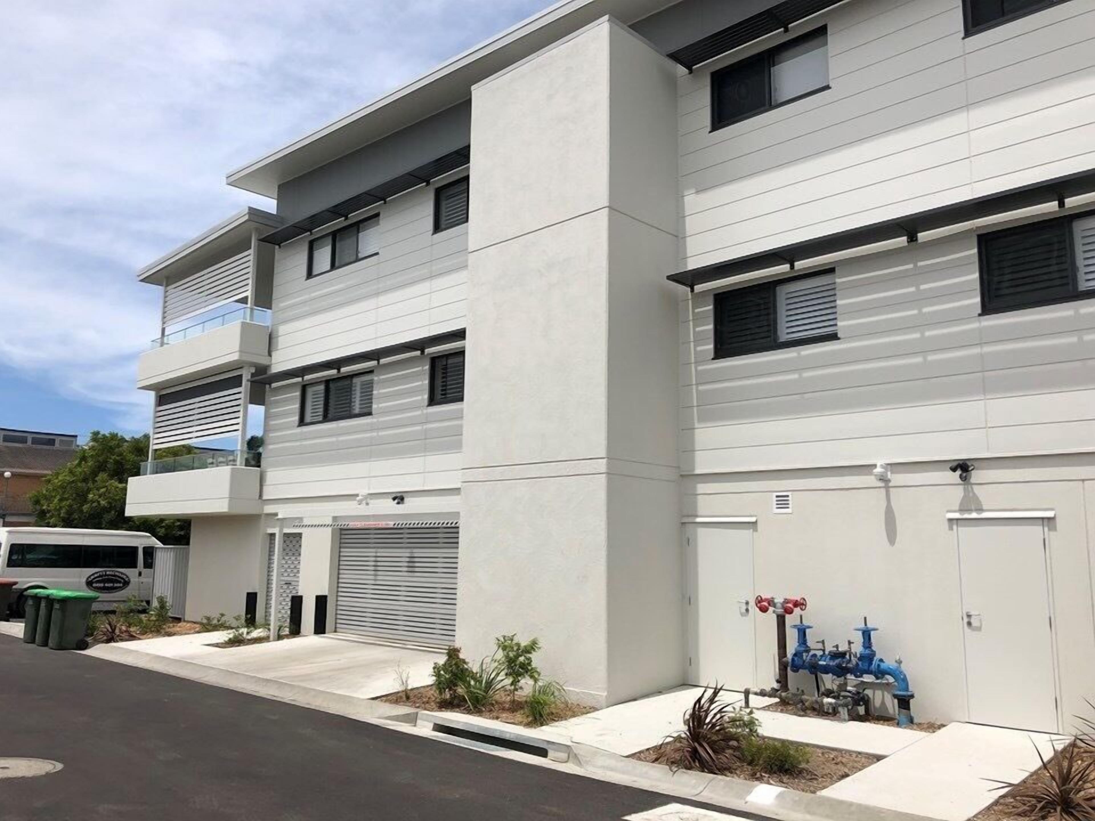 A modern multi-story building with a flat roof, large windows, and a clean, white facade.