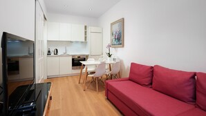 A compact living space with a kitchenette, a dining area, and a red sofa.