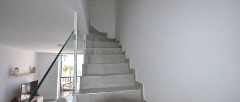 A staircase leading to a balcony with a view of palm trees.