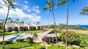 A resort with multiple buildings, a swimming pool, and palm trees.