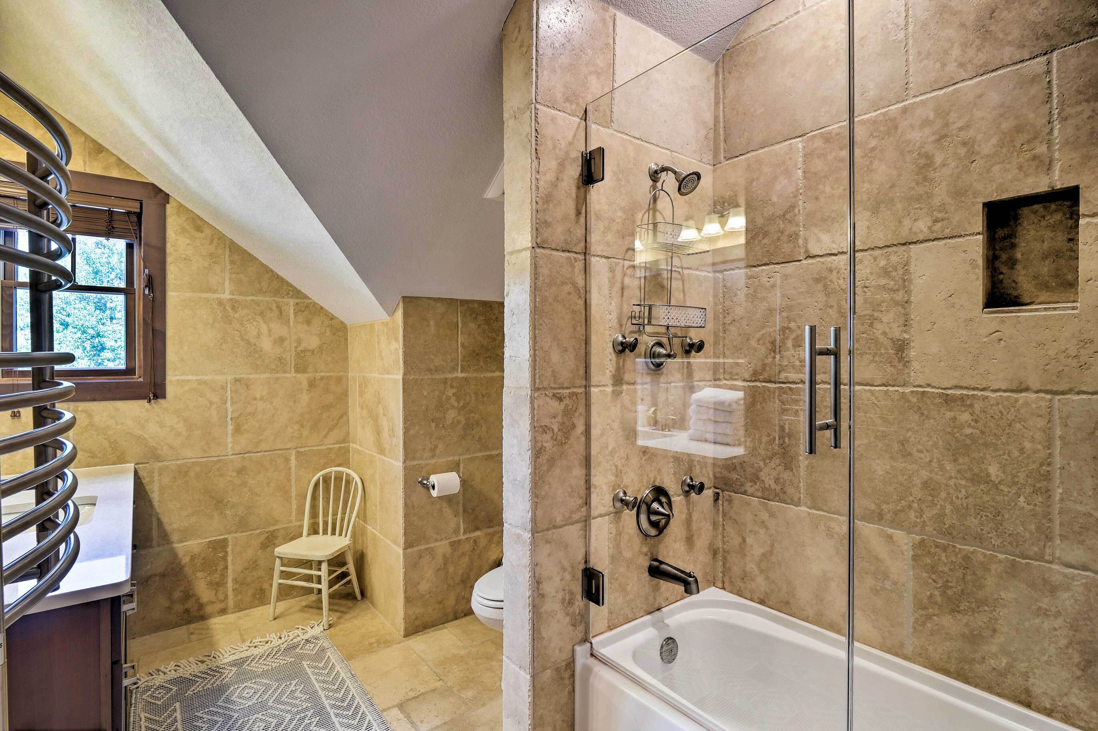Een moderne badkamer met een glazen douchecabine, een badkuip en een toilet.