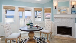 Quarto com vista para o mar, lareira e mesa redonda com cadeiras.