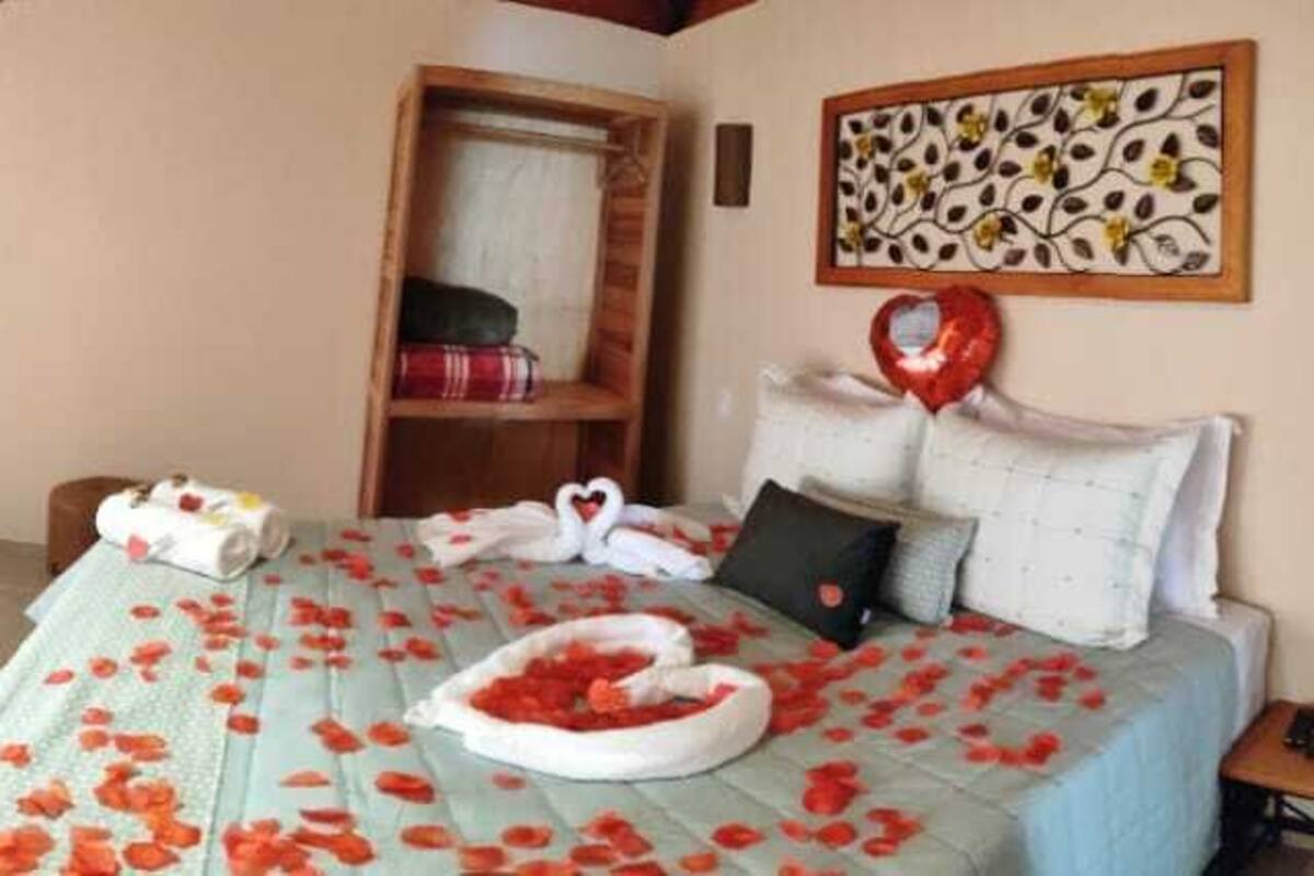 Ein Schlafzimmer mit einem großen Bett, einer Sitzecke mit Sesseln, einer Badewanne und einem Fernseher.