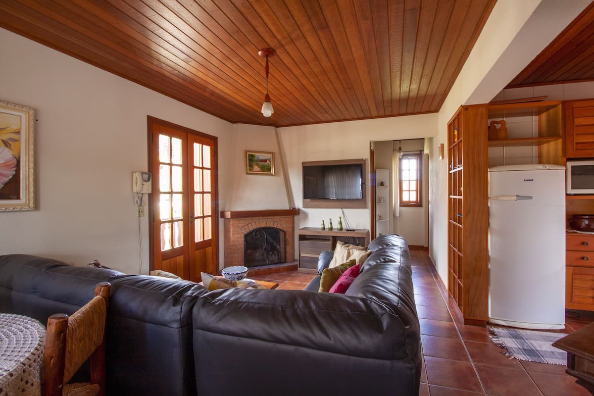 Ein Wohnzimmer mit Kamin, einer Couch, einem Fernseher und Holzsäcken.