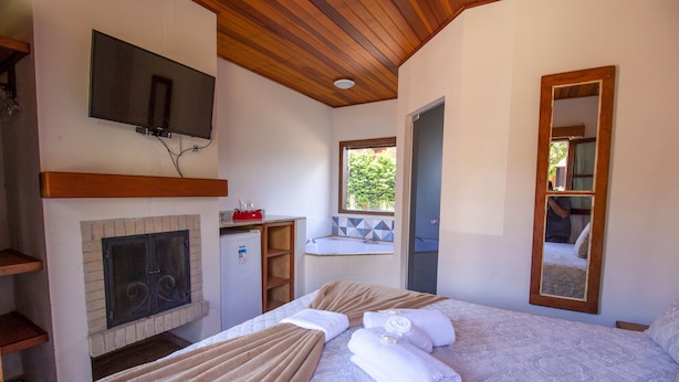 Ein Schlafzimmer mit Kamin, Fernseher und einem großen Spiegel.