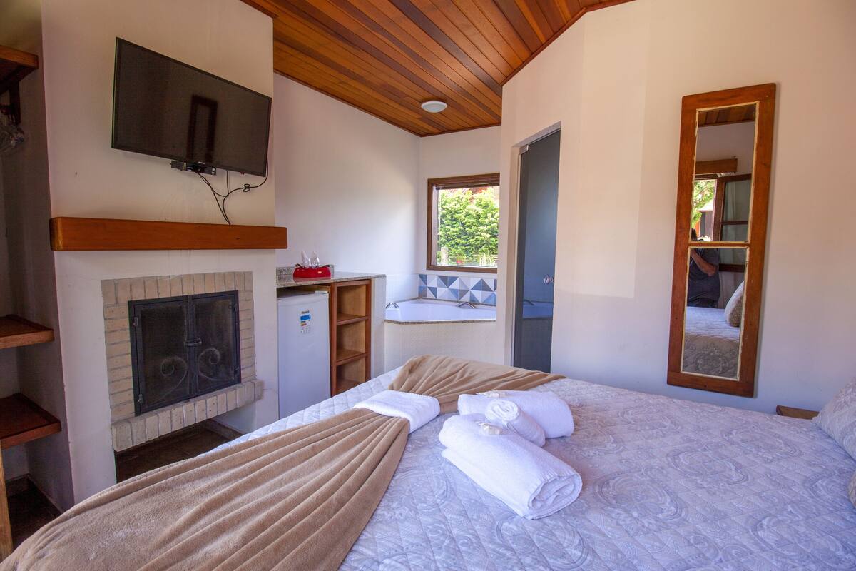Ein Schlafzimmer mit Kamin, Fernseher und einem großen Spiegel.