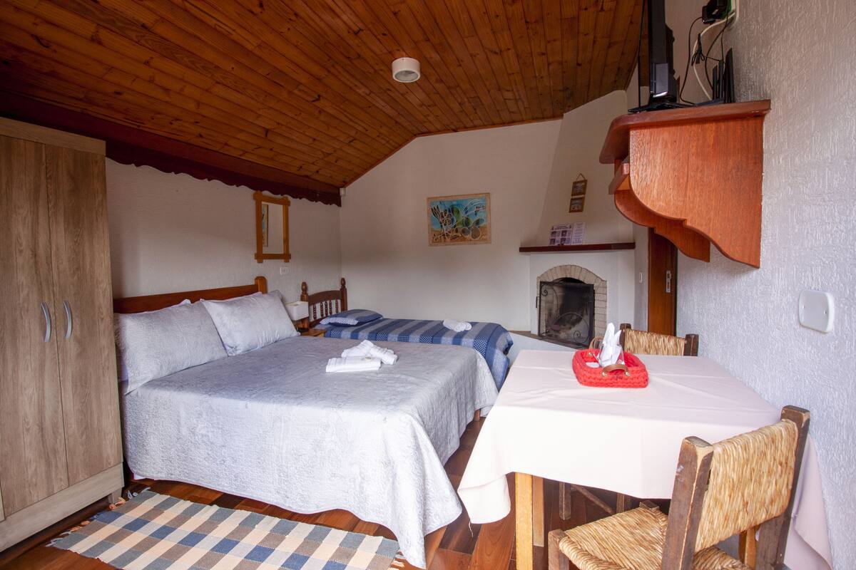 Ein Schlafzimmer mit zwei Betten, einer Holzbalkendecke, einem Tisch mit Stühlen und einem Kamin.