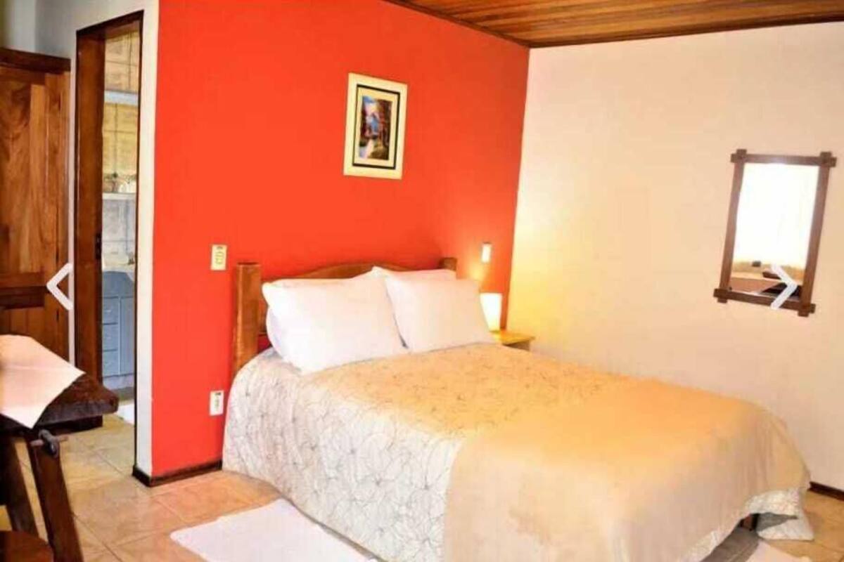 Ein Schlafzimmer mit einem Bett, einem Nachttisch, einem wandmontierten Spiegel und einer Tür zu einem anderen Raum.