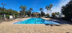 A swimming pool with lounge chairs, palm trees, and a gazebo. - Condo FANTASIA at Reunion Resort Golf Comm. near Disney World  - FREE WiFi (Reunion)