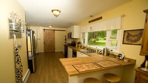 Una cocina con encimeras de madera, una isla integrada con taburetes, un refrigerador y una ventana con vistas al exterior.