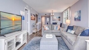 Ein modernes Wohnzimmer mit Flachbildfernseher, grauem Sofa und Couchtisch.