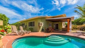 A house with a swimming pool, outdoor furniture, and a covered patio area. - Palm Beach home with private pool (Noord)