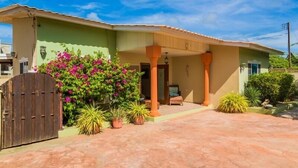 A two-story house with a covered porch, a wooden gate, and various potted plants. - Palm Beach home with private pool (Noord)