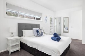 Relax in a serene space with a large bed, white bedding, and a stylish nightstand.