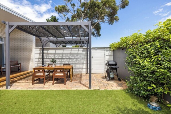 Enjoy dining and socializing under the pergola, with a barbecue grill and comfortable seating for a relaxing outdoor experience.