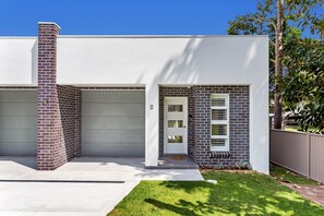 Stylish home with a brick chimney, garage, and beautifully maintained lawn.