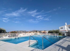 En swimmingpool med ett vitt staket och en klarblå himmel.