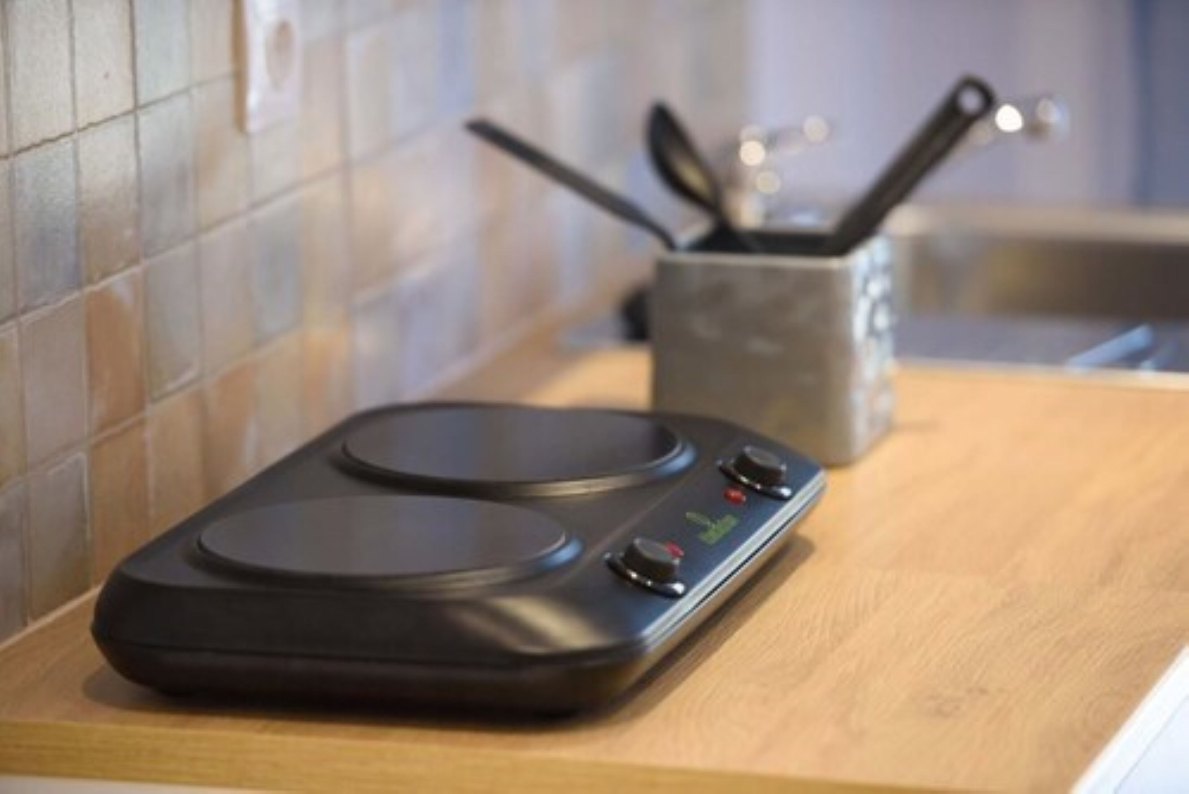 A kitchen with a modern induction cooktop and a utensil holder.