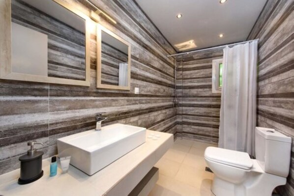 A modern bathroom with a large mirror, a white sink, and a toilet. - Mezza Volta by Estia (Corfu)