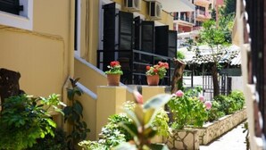 Un carrer estret amb edificis grocs, persianes negres i plantes en testos.