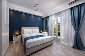 Une chambre à coucher avec un grand lit, une table de chevet, une commode et une fenêtre avec des rideaux.