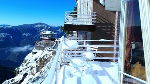 A snow-covered balcony with a view of a mountain range.