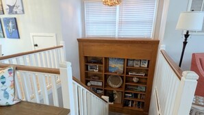 Un escalier menant à une bibliothèque dotée d’étagères en bois et d’un lustre.