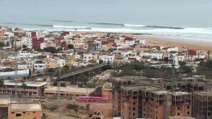 Eine Küstenstadt mit einer Mischung aus Wohngebäuden, von denen einige im Bau sind, und einem Strand im Hintergrund.
