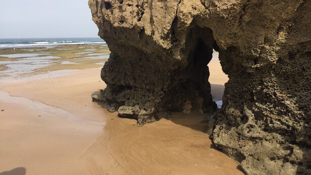 Eine natürliche Felsformation mit einer hohlen Öffnung an einem Sandstrand.