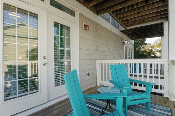 A covered porch with two turquoise Adirondack chairs and a small round table.