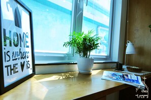 Une citation encadrée accrochée au mur, une plante en pot posée sur un rebord de fenêtre et un magazine sur une table.