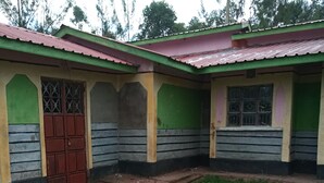 A building with a green and yellow facade, a red door, and a small grassy area in front. - Property is located at kanusin village near Chepeyan pry school,near main roads (Bomet)