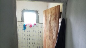A small, narrow bathroom with tiled walls and floor, a wooden door, and a window. - Property is located at kanusin village near Chepeyan pry school,near main roads (Bomet)