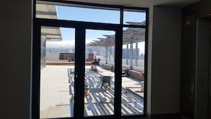 Blick durch ein großes Fenster auf eine Baustelle mit Bauarbeitern und Baumaterialien.