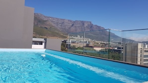 Ein Pool auf dem Dach mit freiem Blick auf eine Stadtlandschaft und Berge im Hintergrund.