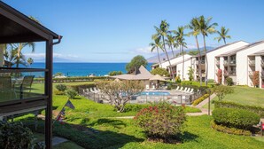 A resort with a pool, palm trees, and a view of the ocean.
