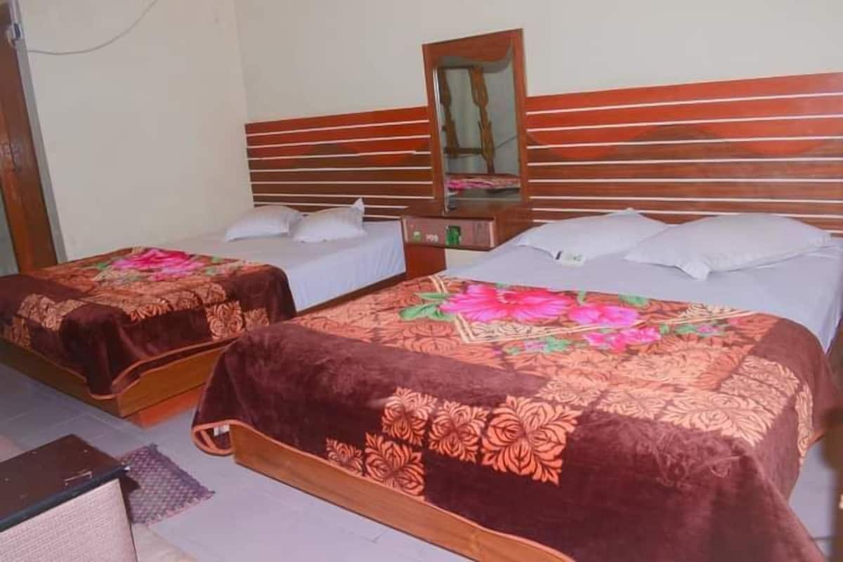 Une chambre d’hôtel avec deux lits simples, chacun doté d’une tête de lit en bois et d’un miroir au-dessus.